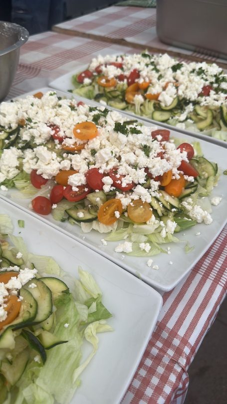 Frischer Salat mit Gurken, Kirschtomaten und Feta auf weißem Teller.