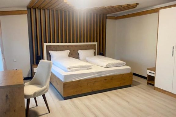 Helles, modernes Zimmer mit Doppelbett und Holzverkleidung. Schreibtisch und Stuhl vorhanden.
