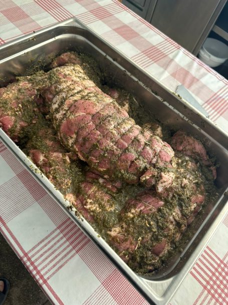 Ein großer Braten mit Kräutermarinade in einer Metallschale.